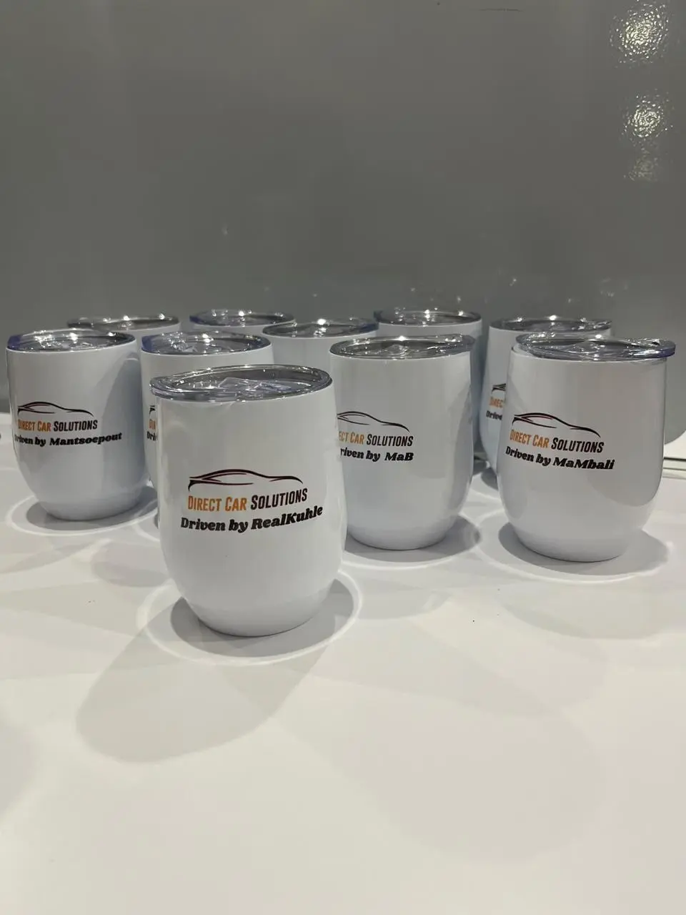 Several short white tumblers with matching business branding